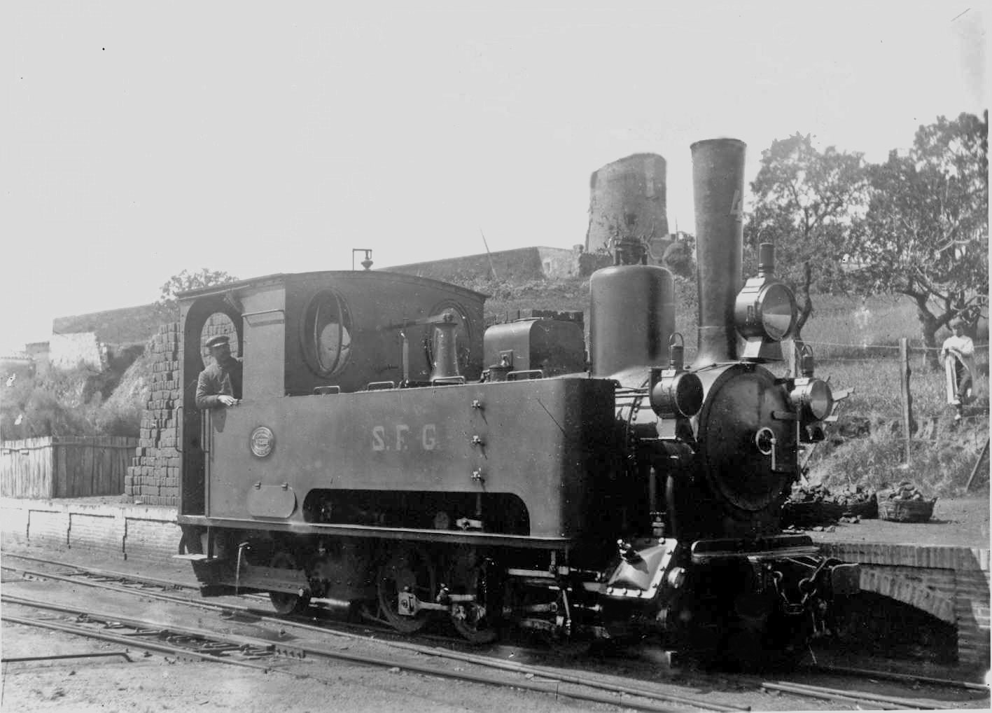 Locomotiva nº 4, modello A6 di fianco alla molla di carico di carbone, in secondo termine la Torre i Sei loro. Foto appartenente all'Archivio municipal di Sant Feliu di GuíxolsLocomotora 4 al costat del moll del carbó