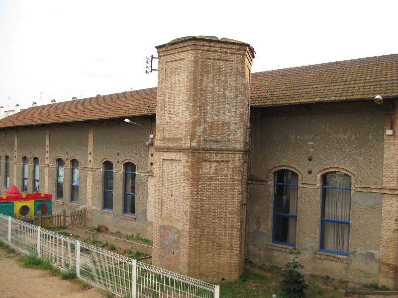 Edificio de los talleres de la estación de Sant Feliu con el tanque de agua en primer plano